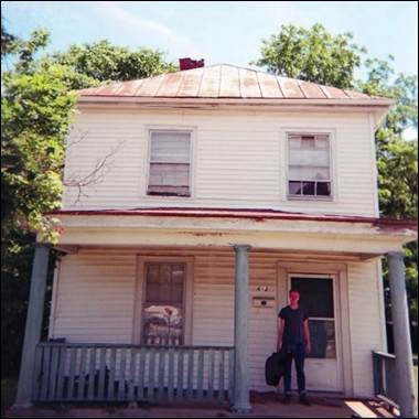 A person standing in front of a house
Description automatically generated