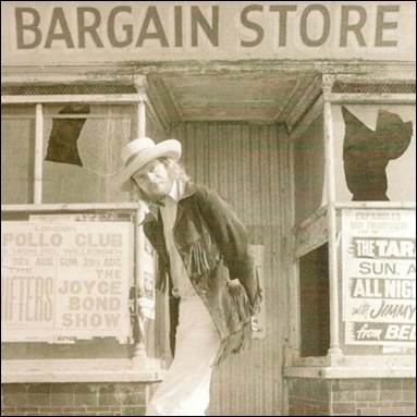 A person in a hat standing in front of a store

Description automatically generated