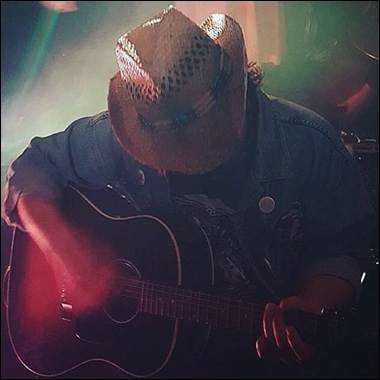 A person playing guitar in a cowboy hat
Description automatically generated