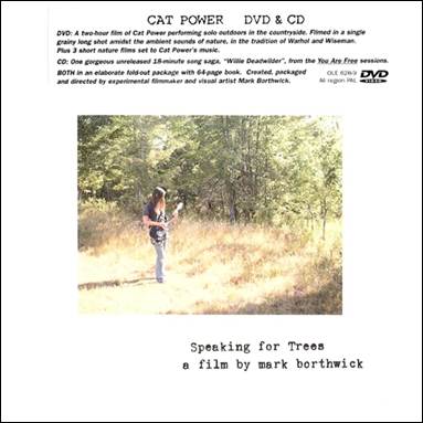 A person holding a guitar in a forest

Description automatically generated