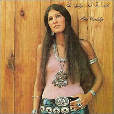 A person with long hair wearing a pink top and silver jewelry
Description automatically generated