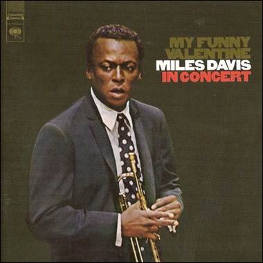 A person in a suit holding a trumpet

Description automatically generated