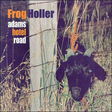 A goat with horns sticking out of the grass
Description automatically generated