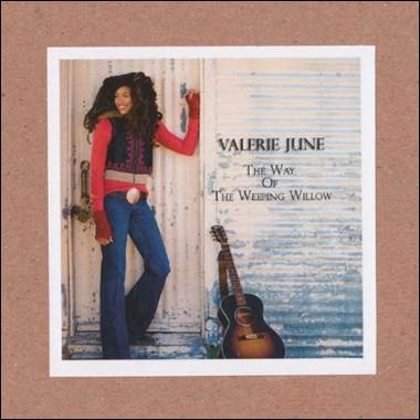 A person leaning against a wall with a guitar
Description automatically generated