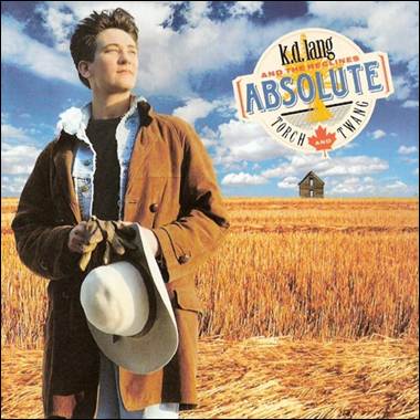 A person in a brown coat holding a hat in a field

Description automatically generated