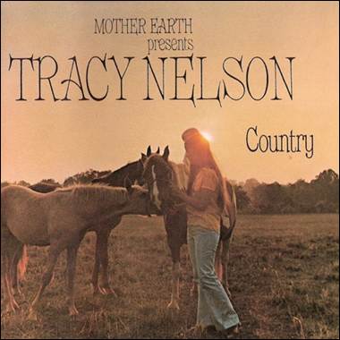 A person standing in a field with horses
Description automatically generated