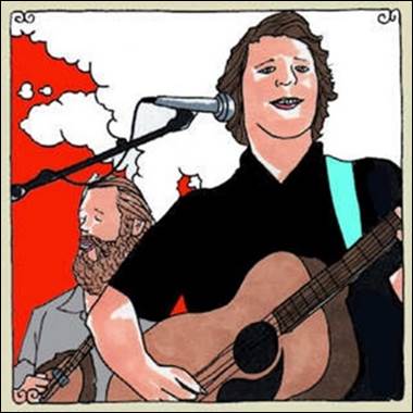 A person playing guitar and singing with a person behind him
Description automatically generated