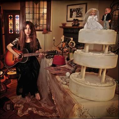 A person playing a guitar in front of a cake
Description automatically generated