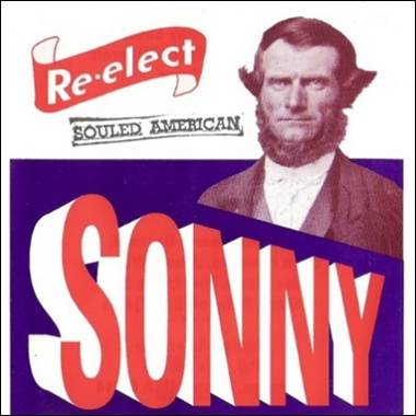 A person with a beard and a purple and blue background
Description automatically generated