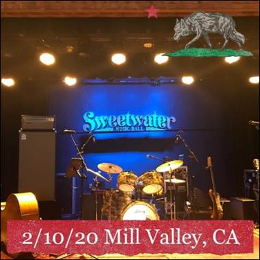 A stage with a drum set and a guitar
Description automatically generated