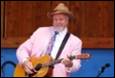 A person in a pink suit playing a guitar

Description automatically generated
