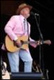 A person in a pink suit playing a guitar

Description automatically generated